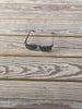 A pair of dark-framed sunglasses with dark lenses resting on weathered wooden planks.