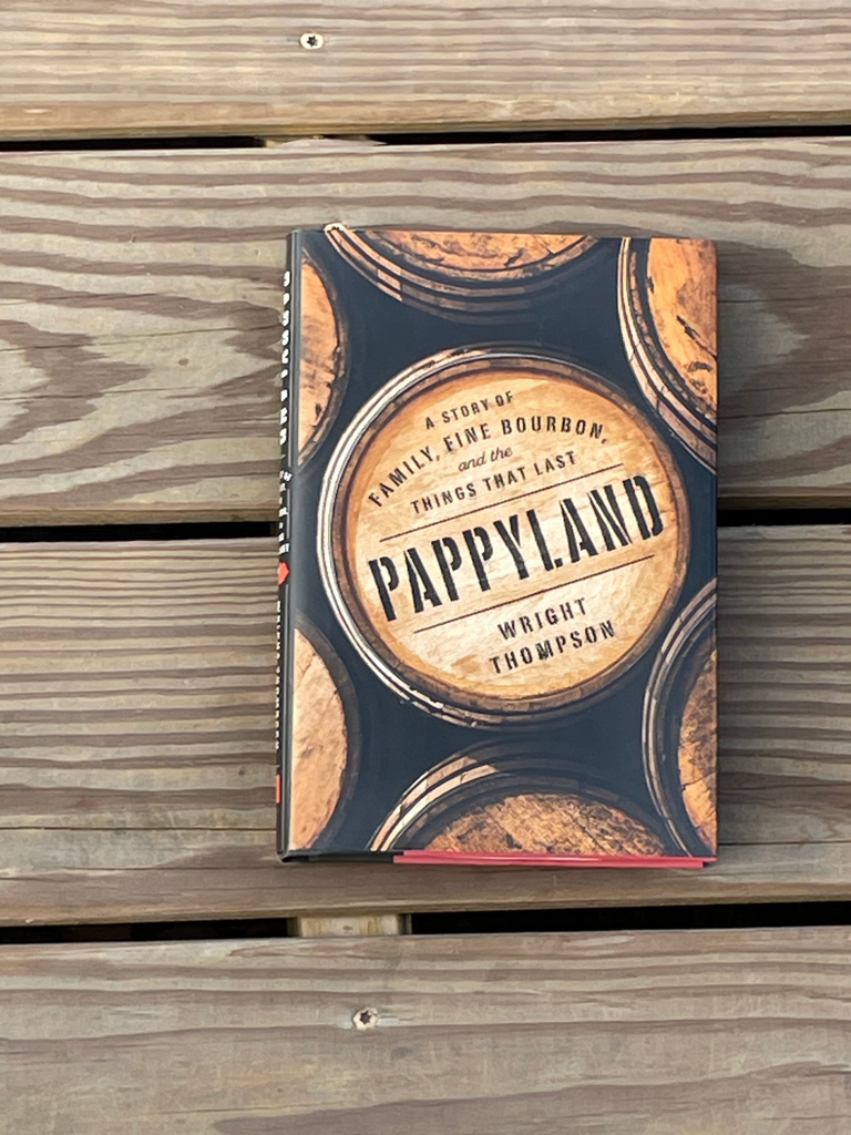 A hardcover book titled 'Pappyland' by Wright Thompso featuring a rustic barrel graphic design, resting on a weathered wooden plank surface.